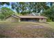 Rear exterior of home with a large screened lanai and lush, mature trees providing shade at 1204 Ballinger Rd, Lutz, FL 33548