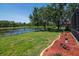 Manicured lawn with a lake view, beautiful flowerbeds, and mature trees at 12309 Creek Edge Dr, Riverview, FL 33579