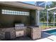 An outdoor kitchen with stainless steel grill and brick facade is the perfect place to entertain by the pool at 12309 Creek Edge Dr, Riverview, FL 33579