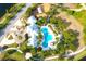 Aerial view of community pool with clubhouse, palm trees, walking paths, and playground for residents to enjoy at 13327 Waterleaf Garden Cir, Riverview, FL 33579