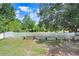 Lush green backyard featuring a white picket fence, garden beds, and mature trees at 13523 Prestwick Dr, Riverview, FL 33579