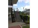 Exterior staircase with black railing leading to upper-level condos, surrounded by lush landscaping and mature trees at 138 36Th N Ave # 206W, St Petersburg, FL 33704