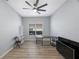 Bright bedroom featuring a ceiling fan, wood floors, a sleek black desk, and a large sunlit window at 17809 Sandpine Trace Way, Tampa, FL 33647