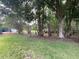 Backyard view with lush lawn, bordered by trees and showing a patio area with outdoor seating at 17933 Eagle Ln, Lutz, FL 33558
