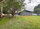 Exterior view of house with lush lawn, trees, and gray colored back patio with outdoor seating at 17933 Eagle Ln, Lutz, FL 33558