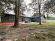Exterior view of house with patio, featuring Adirondack chairs, a firepit, and surrounding trees at 17933 Eagle Ln, Lutz, FL 33558