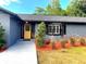 Inviting entrance with a bright yellow door, fresh landscaping, and modern planters at 17933 Eagle Ln, Lutz, FL 33558