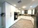White kitchen featuring granite countertops, stainless appliances and wood-look tile at 17933 Eagle Ln, Lutz, FL 33558