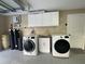 Convenient garage laundry room with modern washer, dryer, sink, and white cabinets for storage at 17933 Eagle Ln, Lutz, FL 33558