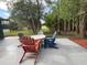 Outdoor patio featuring Adirondack chairs and a white fire pit, surrounded by green trees at 17933 Eagle Ln, Lutz, FL 33558