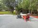 Outdoor patio featuring Adirondack chairs and a white fire pit, surrounded by green trees at 17933 Eagle Ln, Lutz, FL 33558