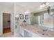 Bright bathroom with double vanity, bathtub, glass block window, and walk-in closet access at 19156 Dove Creek Dr, Tampa, FL 33647