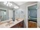 Well-lit bathroom featuring dual sinks, neutral tones, and a view to the bedroom at 19156 Dove Creek Dr, Tampa, FL 33647