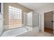 Bright bathroom featuring a luxurious bathtub, glass block window, and a separate shower at 19156 Dove Creek Dr, Tampa, FL 33647