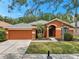 Charming single-story home with an attached two-car garage, arched entryway, and lush landscaping for appealing curb appeal at 19156 Dove Creek Dr, Tampa, FL 33647