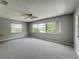 Carpeted living room with ceiling fan and large sunny windows at 2014 Hampstead Cir, Sun City Center, FL 33573