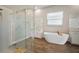 Bright bathroom featuring a glass-enclosed shower, soaking tub, and white vanities at 21648 Snowy Orchid Ter, Land O Lakes, FL 34637