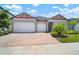 Beautiful single-story home featuring a three-car garage, brick driveway, and landscaped garden at 21648 Snowy Orchid Ter, Land O Lakes, FL 34637