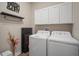 A laundry room with upper cabinets, modern washer and dryer, and decorative shelving at 21648 Snowy Orchid Ter, Land O Lakes, FL 34637