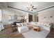 Open-concept living room featuring a large sectional, ceiling fan, and views into the adjacent kitchen at 21648 Snowy Orchid Ter, Land O Lakes, FL 34637