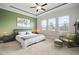 A view of the main bedroom, featuring three windows, an accent chair and a carpeted floor at 21648 Snowy Orchid Ter, Land O Lakes, FL 34637