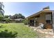 Large backyard with green grass, mature trees, and the home's exterior with various equipment at 2287 Demaret Dr, Dunedin, FL 34698