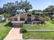 Striking two-story home with stone facade, mature trees, and well-manicured lawn offers curb appeal at 2287 Demaret Dr, Dunedin, FL 34698