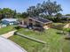 An elevated exterior view of the home, landscaped front yard, and a paved driveway at 2287 Demaret Dr, Dunedin, FL 34698