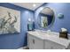 Stylish bathroom featuring a blue wall, decorative mirror, and vanity with sink adds a touch of luxury at 2412 Hammock Pine Blvd, Clearwater, FL 33761