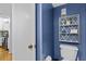 Powder room featuring vibrant blue walls, a white toilet, and a decorative shelf adds character to the space at 2412 Hammock Pine Blvd, Clearwater, FL 33761