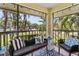 Inviting screened patio with cozy seating, patterned rug, and serene views of the surrounding landscape and neighborhood at 2412 Hammock Pine Blvd, Clearwater, FL 33761