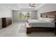 Bedroom with tray ceiling featuring tiled floors, large window and dark wood furniture at 2512 High Tides Way, Wesley Chapel, FL 33543