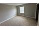 This bedroom has neutral carpet, baseboards, and walls, along with a window to let light in at 2557 Cedar Cypress Ct, Tampa, FL 33618