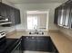 Kitchen with dark cabinets, stone countertops, and a double sink beneath a view-through window at 2557 Cedar Cypress Ct, Tampa, FL 33618