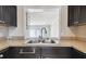 Close-up of kitchen sink featuring stainless steel sink, dark cabinets and tile countertops at 2557 Cedar Cypress Ct, Tampa, FL 33618