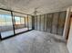 Living room features exposed concrete, bare studs, and sliding glass doors with views of nearby greenery at 2621 Cove Cay Dr # 206, Clearwater, FL 33760
