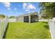 Expansive backyard featuring a well-maintained lawn, white fencing, and a screened-in patio for outdoor enjoyment at 26749 Middleground Loop, Wesley Chapel, FL 33544