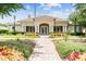The community clubhouse features a brick pathway, white pillars, colorful landscaping, and ample windows at 26749 Middleground Loop, Wesley Chapel, FL 33544