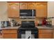 Kitchen showcasing black appliances, wood cabinetry, and tile countertops for a functional cooking space at 26749 Middleground Loop, Wesley Chapel, FL 33544