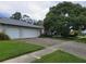 Home's exterior featuring a well-manicured lawn, two car garage, and mature shade tree at 3200 Sandy Ridge Dr, Clearwater, FL 33761
