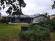 Backyard view of screened-in pool, lush landscaping and a charming grey home at 3200 Sandy Ridge Dr, Clearwater, FL 33761