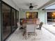Covered patio with outdoor dining set, ceiling fan, and view through sliding doors to kitchen and living area at 3200 Sandy Ridge Dr, Clearwater, FL 33761