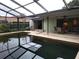 Outdoor pool with a screened in porch, greenery, and surrounding patio furniture and view of the home at 3200 Sandy Ridge Dr, Clearwater, FL 33761
