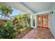 Inviting front porch with brick flooring, colorful plants, and a bright orange front door at 3749 Mckay Creek Dr, Largo, FL 33770