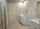 Bright bathroom featuring double sinks with white vanities, a glass shower, and neutral tiling at 3776 Maxwell Park Dr, Sun City Center, FL 33573