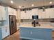 Spacious kitchen features stainless steel appliances, white cabinetry and island with pendant lights at 3776 Maxwell Park Dr, Sun City Center, FL 33573