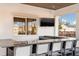 An outdoor kitchen with granite countertops, seating for six, and a mounted TV provides a great space to relax and entertain at 3776 Maxwell Park Dr, Sun City Center, FL 33573