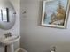 Charming powder room with stylish round mirror, pedestal sink, and elegant wall decor painting at 3776 Maxwell Park Dr, Sun City Center, FL 33573