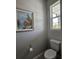 Powder room with toilet, framed painting, and window providing natural light for an inviting space at 3776 Maxwell Park Dr, Sun City Center, FL 33573