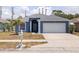 Charming blue home with a well-manicured lawn, palm tree, and a two-car garage at 4555 Hannah Ln, St Petersburg, FL 33709